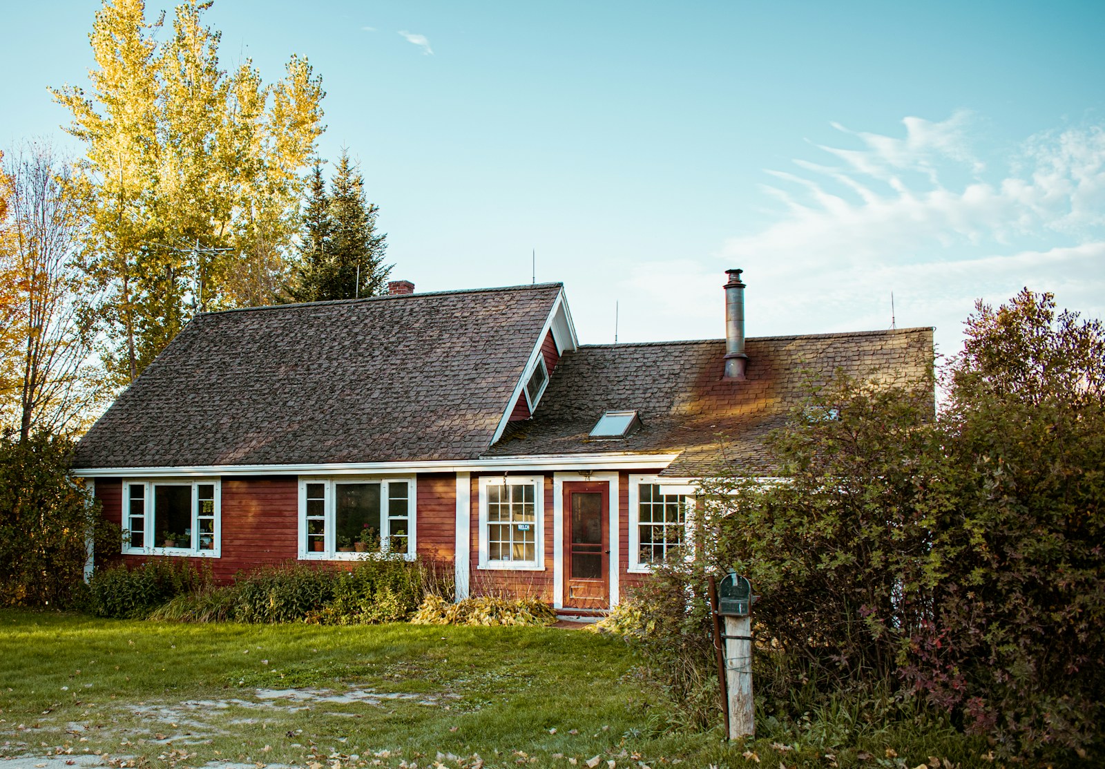 A cozy red house sits among trees.